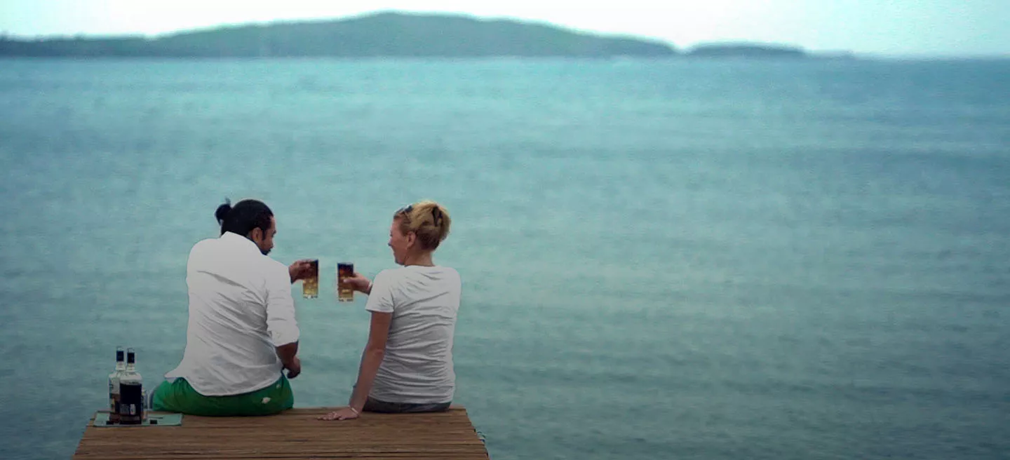 Image of a man and a woman on a dock with Cruzan mixed cocktails after a Cruzan distillery tour.