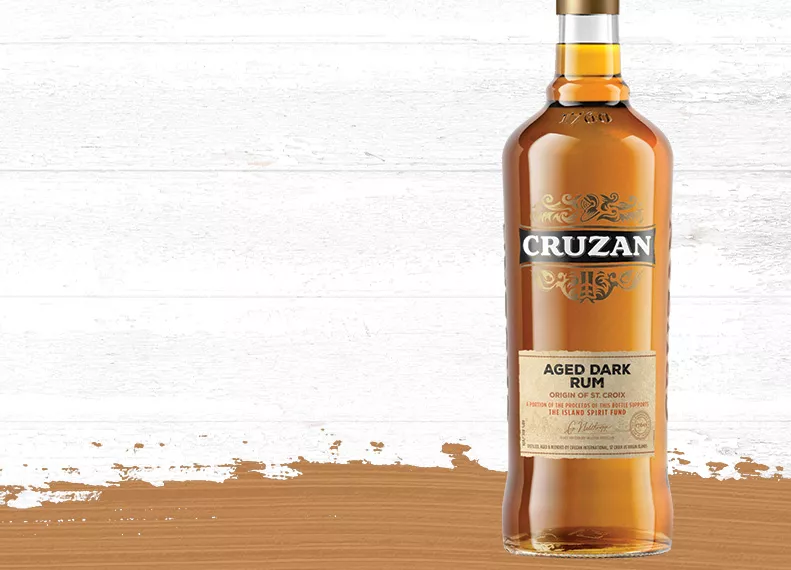 Cruzan Aged Dark Rum - Origin of St. Croix glass bottle set against a whitewashed wood background.