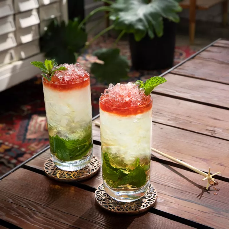 Two Queen's Park Swizzle cocktails set on a table, ready to enjoy.