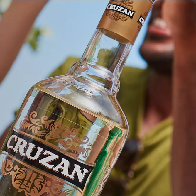 Person holding Cruzan rum clear bottle with a gold Cruzan label
