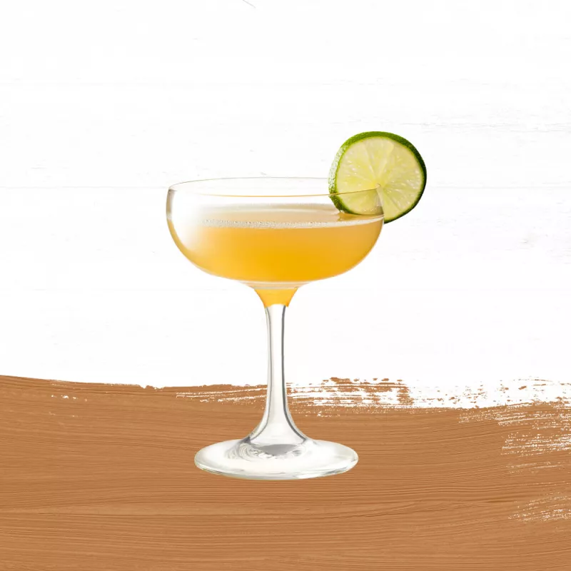 Cruzan daiquiri in a clear class garnished with a slice of lime set against a light oak barrel background with a muted tan paint swash.