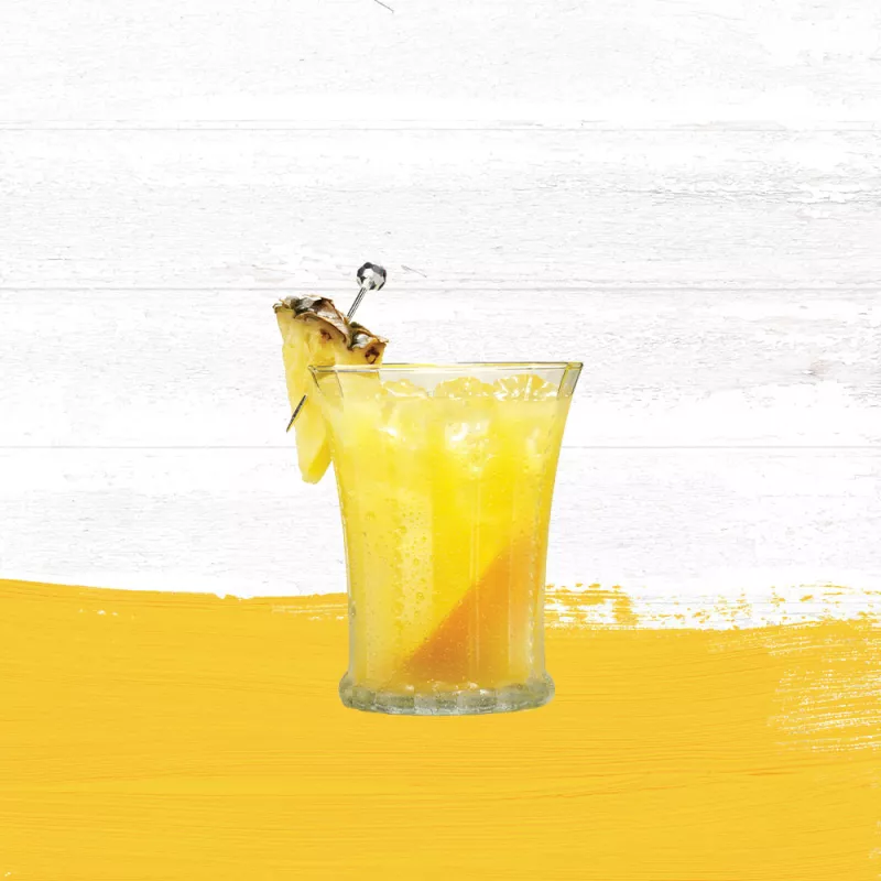 Endless Summer Punch cocktail in a clear glass garnished with pineapple set against a whitewashed wood background and mango hued paint swash.