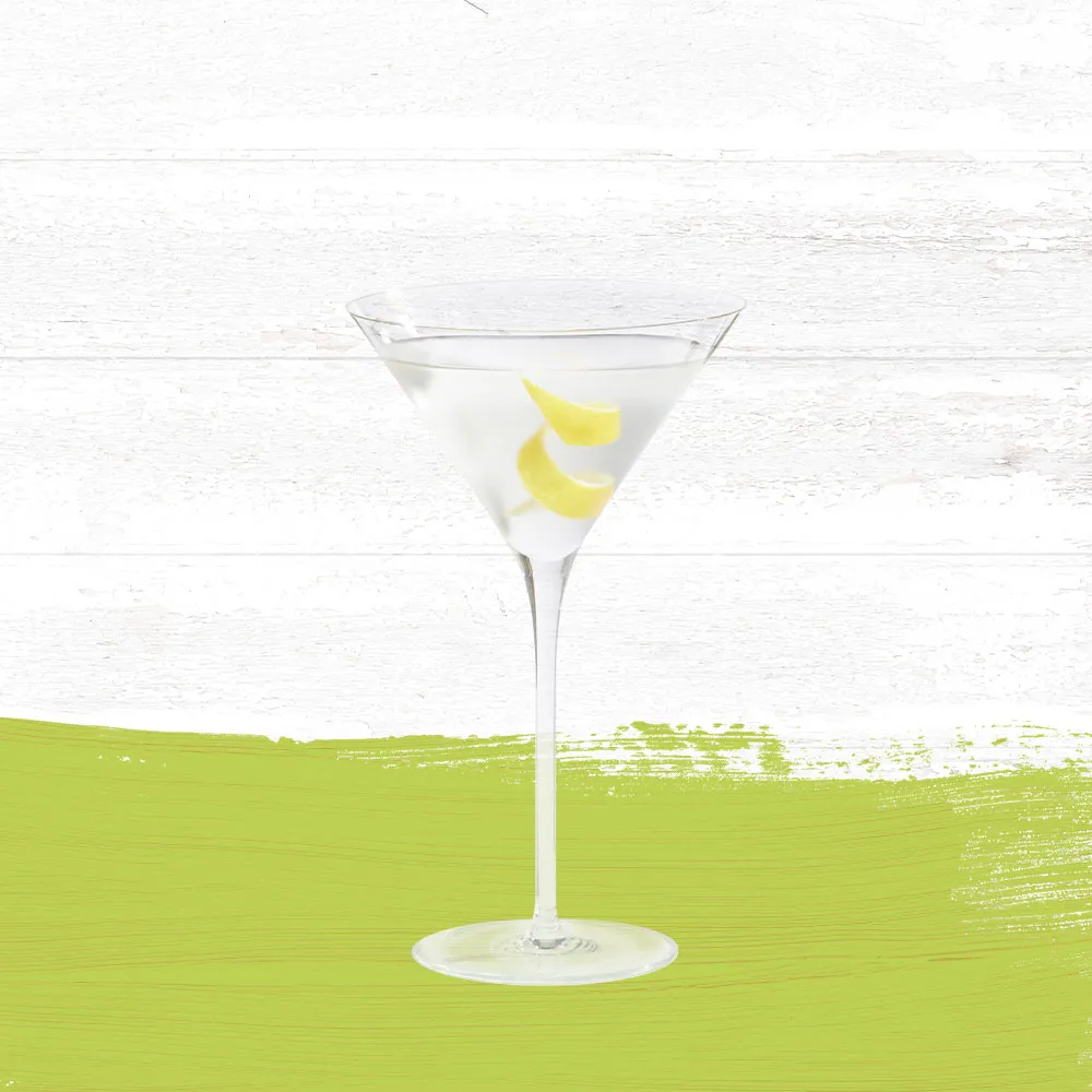 Guava Sidecar cocktail served in a clear martini glass garnished with a lemon twist against a whitewashed wood background with a lime green paint swash.