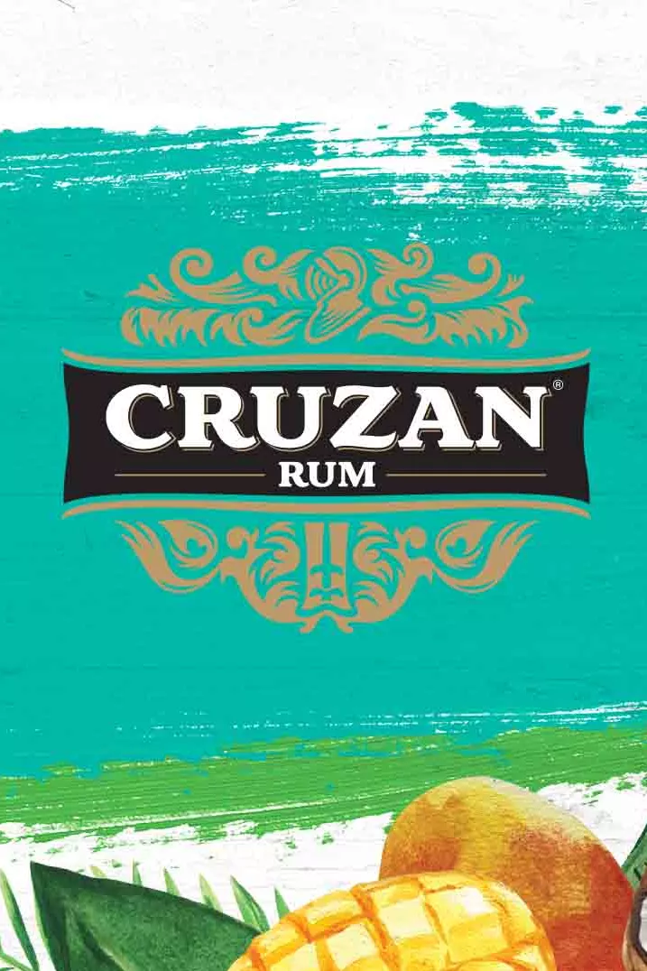 Cruzan Rum logo set against a whitewashed wood background with a paint swash and tropical fruit in the lower right hand corner.