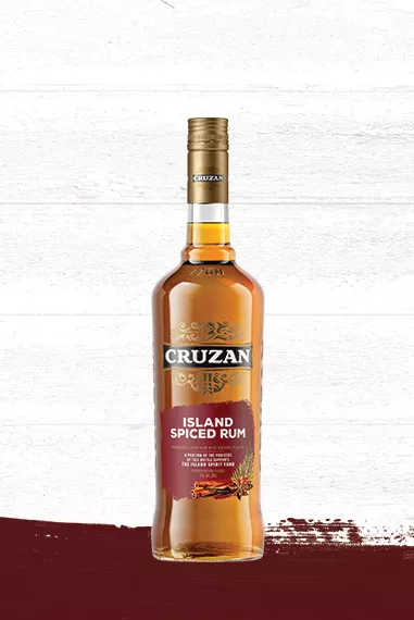 Cruzan® Island Spiced Rum glass bottle set against a whitewashed wood background with a warm crimson paint swash.