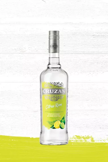 Clear bottle of Cruzan Citrus Rum against a whitewashed wood background with a lemon-lime yellow paint swash.