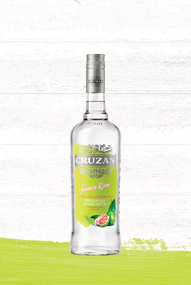 Whitewashed wood background with Cruzan Guava Rum in a clear glass bottle with a lime green label adorned with a guava image.