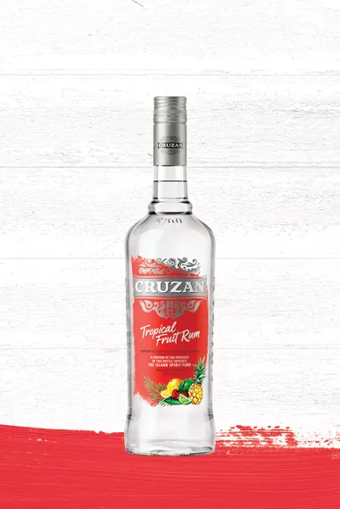 Cruzan Tropical Fruit Rum clear glass bottle with a bold red label adorned with tropical fruit set against a whitewashed wood background with a red paint swash.