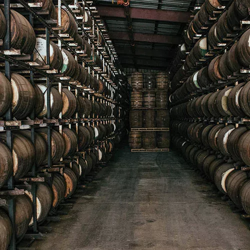 Multiple rum barrels sitting on top of each other in an aging room.